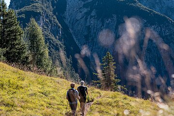 Ein Paar wandert über eine Almwiese mit Blick auf den Gipfel