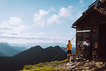 Ein Wanderer genießt die Aussicht auf die Bergwelt bei Sonnenschein