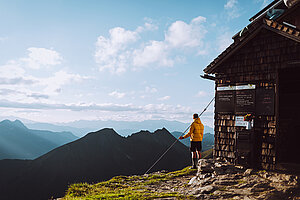 Ein Wanderer genießt die Aussicht auf die Bergwelt bei Sonnenschein